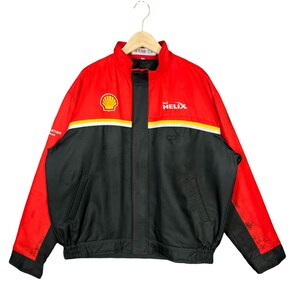 May include: A red and black jacket with a Shell Helix logo. The jacket has a zipper closure and two pockets. The jacket is made of a water-resistant material.