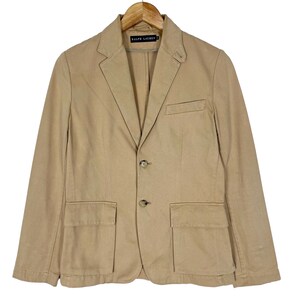 May include: A tan blazer with two front pockets and three buttons. The blazer has a label that reads "Ralph Lauren" on the inside.