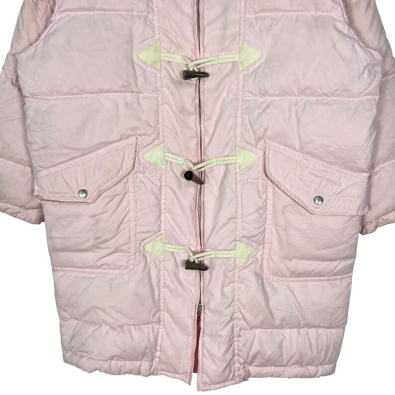 K&ouml;nnte beinhalten: Eine rosafarbene Steppjacke mit Rei&szlig;verschluss und Knebelverschl&uuml;ssen. Die Jacke hat zwei Taschen und ein wei&szlig;es Logo auf der rechten Tasche.