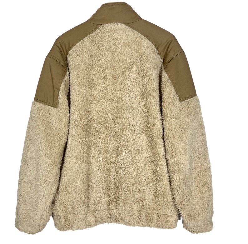 May include: A beige fleece jacket with brown fabric panels on the shoulders and arms. The jacket has a high collar and a zipper closure.