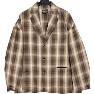 Può includere: Un blazer a quadri marroni e beige con quattro bottoni e due tasche a toppa. Il blazer ha un'etichetta con la scritta "Pendleton" in lettere dorate.