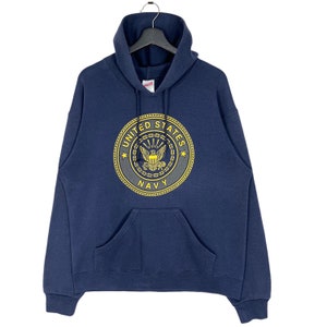 Könnte beinhalten: Ein marineblauer Kapuzenpullover mit einem gelbstickten Siegel der US Navy auf der Vorderseite.
