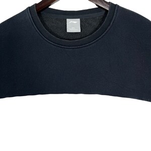 May include: Black sweatshirt with a crew neck and a white label with the text "2XL" on the front.