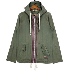 May include: A green hooded jacket with a zip fastening and a white drawstring. The zip has a colourful embroidered design.