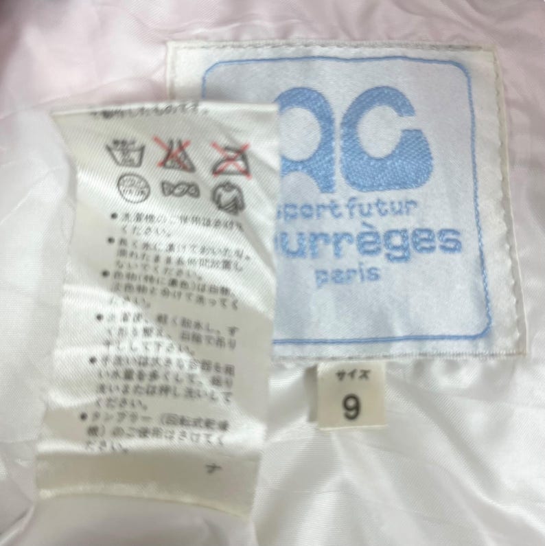 K&ouml;nnte beinhalten: Wei&szlig;es Etikett mit japanischem Text und Pflegehinweisen. Ein blaues Etikett mit dem Text "Sport futur Courr&egrave;ges Paris" und ein wei&szlig;es Etikett mit dem Text "Gr&ouml;&szlig;e 9".