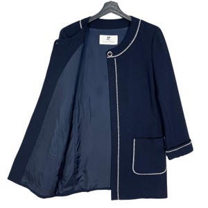 May include: A navy blue blazer with a white trim around the neckline, cuffs, and pockets. The blazer has a single button closure and a label that reads "Courr&egrave;ges".