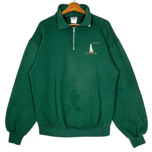 Puede incluir: Una sudadera verde con cremallera de 1/4 con un logotipo bordado en oro que dice "Chicago" y "Kennebunkport, Maine".