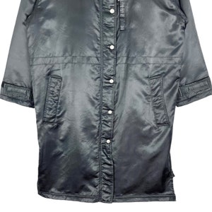 May include: A black satin jacket with a button-up front and long sleeves. The jacket has two pockets on the front and a zipper closure at the neck.