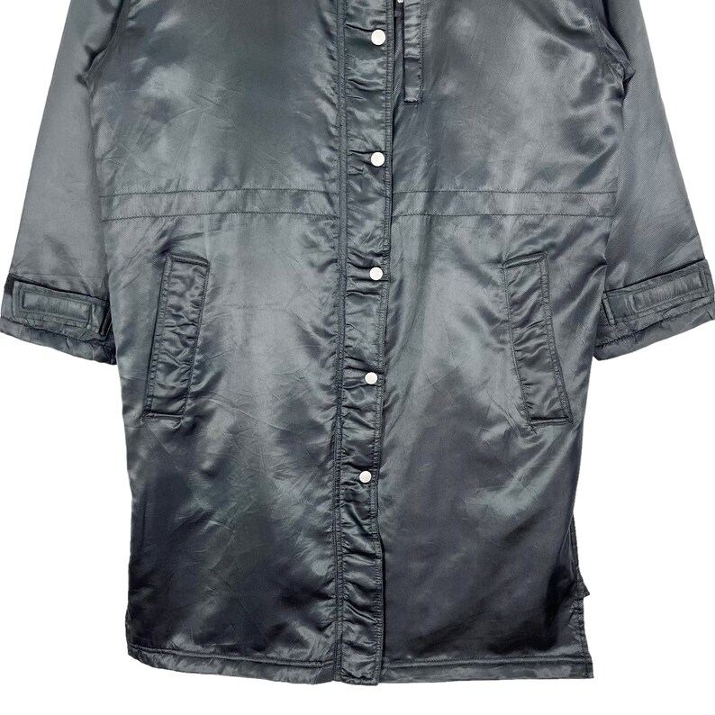 May include: A black satin jacket with a button-up front and long sleeves. The jacket has two pockets on the front and a zipper closure at the neck.
