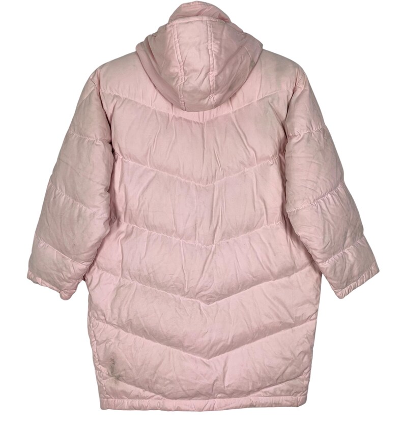 K&ouml;nnte beinhalten: Eine rosafarbene Daunenjacke mit Kapuze und Steppdesign. Die Jacke hat eine lange L&auml;nge und eine lockere Passform.