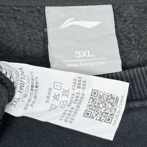May include: White tag with black text and a black and white logo. The tag has the text "3XL 190/104A", "www.lining.com", "3XL", and "MADE IN CHINA". The tag also has a QR code and washing instructions.