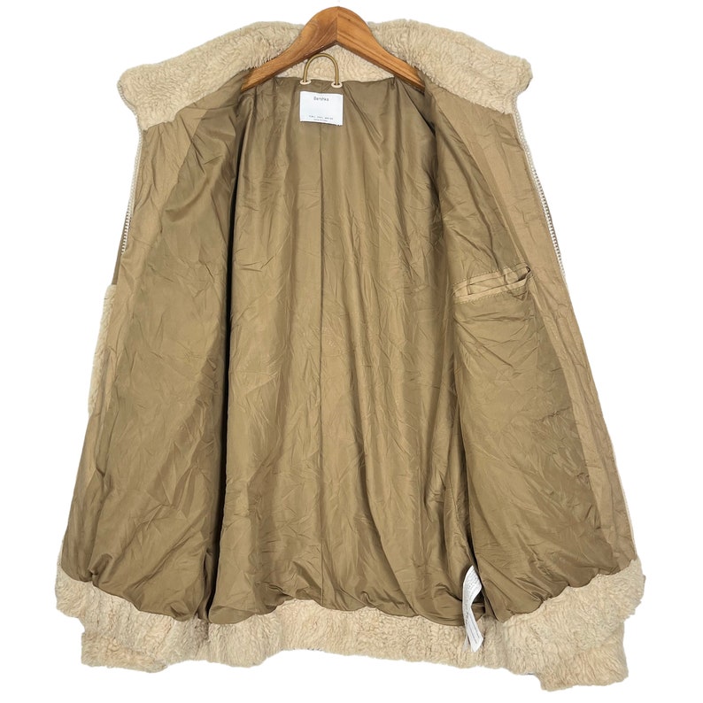 May include: A brown faux fur lined jacket with a zipper closure. The jacket is unbuttoned and the lining is visible. The jacket has a pocket on the inside.