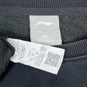 May include: A white tag with black text and a logo. The tag says "3XL 190/104A", "WDG654", "www.lining.com", and "MADE IN CHINA". The tag also has washing instructions and a QR code.