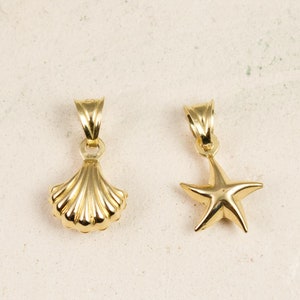 Może przedstawiać: Dwa złote zawieszki, jeden w kształcie muszli, a drugi w kształcie rozgwiazdy.