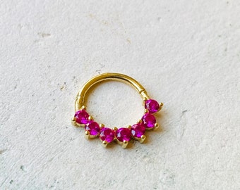 May include: Gold septum ring with a row of pink gemstones.
