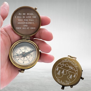 May include: A brass compass with a quote engraved on the lid: "As he read, I fell in love the way you fall asleep: slowly, and then all at once". The compass is open and the needle is pointing north. The other side of the compass has a mountain scene with the words "adventure awaits" engraved on it.