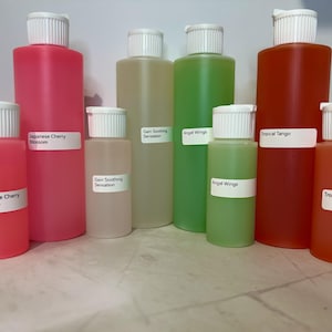 May include: Assortment of colorful liquid bottles with white labels. The labels read "Japanese Cherry Blossom", "Gain Soothing Sensation", "Angel Wings", and "Tropical Tango". The bottles are various sizes and filled with pink, green, and orange liquids.