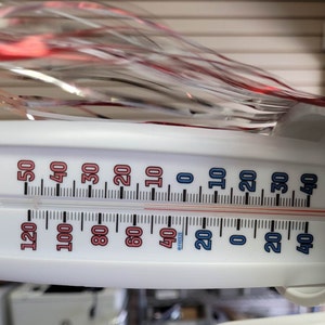 May include: A white thermometer with a red and blue scale shows a temperature of 20 degrees Fahrenheit and 0 degrees Celsius.