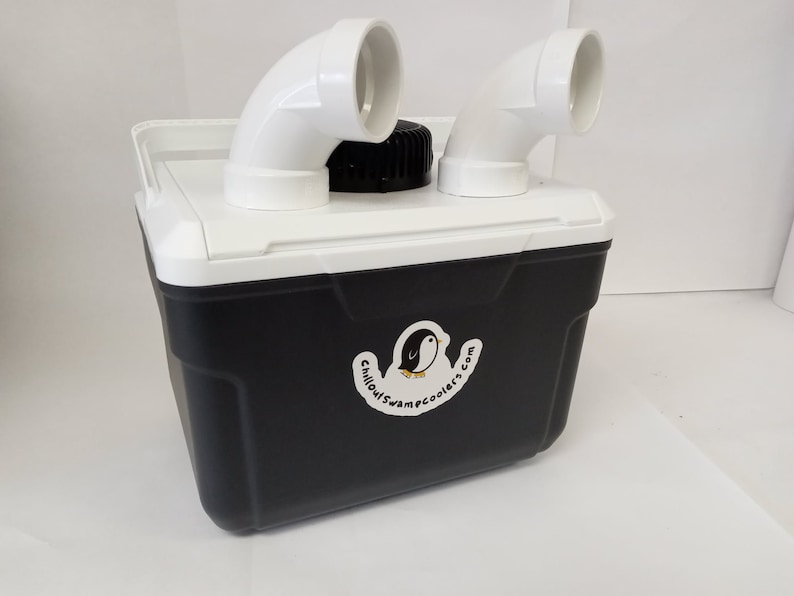 May include: A black and white cooler with a white lid and two white PVC pipes attached to the top. The cooler has a sticker on the side that says "Chilloutcampcoolers.com" and features a cartoon penguin.