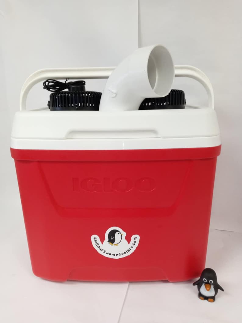 May include: A red Igloo cooler with two black fans and a white vent pipe. The cooler has a sticker that says "Chillout Swamp Coolers.com" with a penguin logo. A small penguin figurine is in the foreground.
