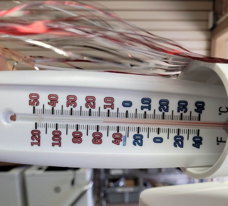May include: A white thermometer displaying both Fahrenheit and Celsius scales. The temperature reads approximately 40&deg;F and 4&deg;C. The thermometer has red and blue markings, with the word "FREEZE" visible.