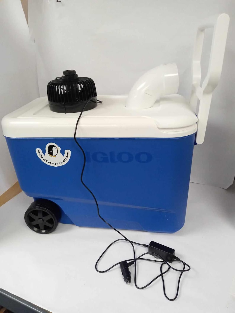 May include: A blue and white Igloo cooler with a black fan, white handle, and a white curved vent. The cooler has a black wheel and a power cord with a car adapter. The cooler has the Igloo logo on the side.