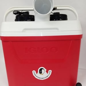 May include: A red Igloo cooler with two fans and a white tube on top. The cooler has a sticker that says "chilloutswamcoolers.com" with a penguin logo. A small penguin figurine is in the foreground.
