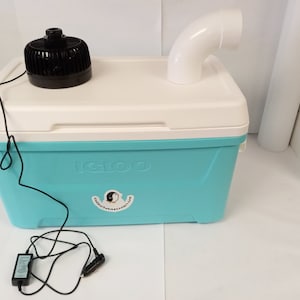 May include: A blue Igloo cooler with a white lid and a black fan on top. A white PVC pipe is attached to the cooler. A black power cord is connected to the fan and a black power adapter is on the floor.