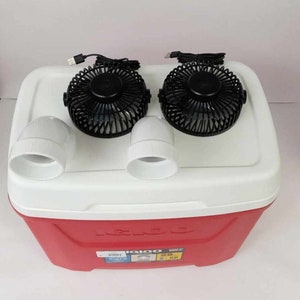 May include: A red Igloo cooler with two black USB-powered fans attached to the top. The fans have white plastic housings and are connected to the cooler with white PVC pipes.