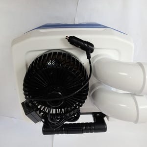 Peut inclure: Un climatiseur portable avec un corps blanc, un dessus bleu et deux sorties d'air blanches. Il comprend un ventilateur noir et un cordon d'alimentation noir avec un adaptateur de voiture. Une poign&eacute;e noire est fix&eacute;e en bas.