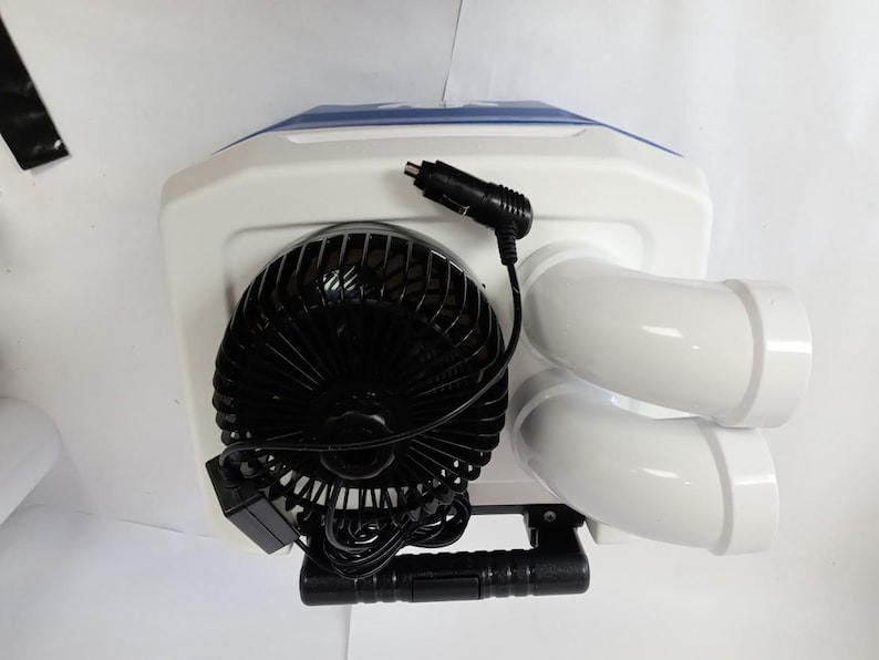 Peut inclure: Un climatiseur portable avec un corps blanc, un dessus bleu et deux sorties d'air blanches. Il comprend un ventilateur noir et un cordon d'alimentation noir avec un adaptateur de voiture. Une poign&eacute;e noire est fix&eacute;e en bas.