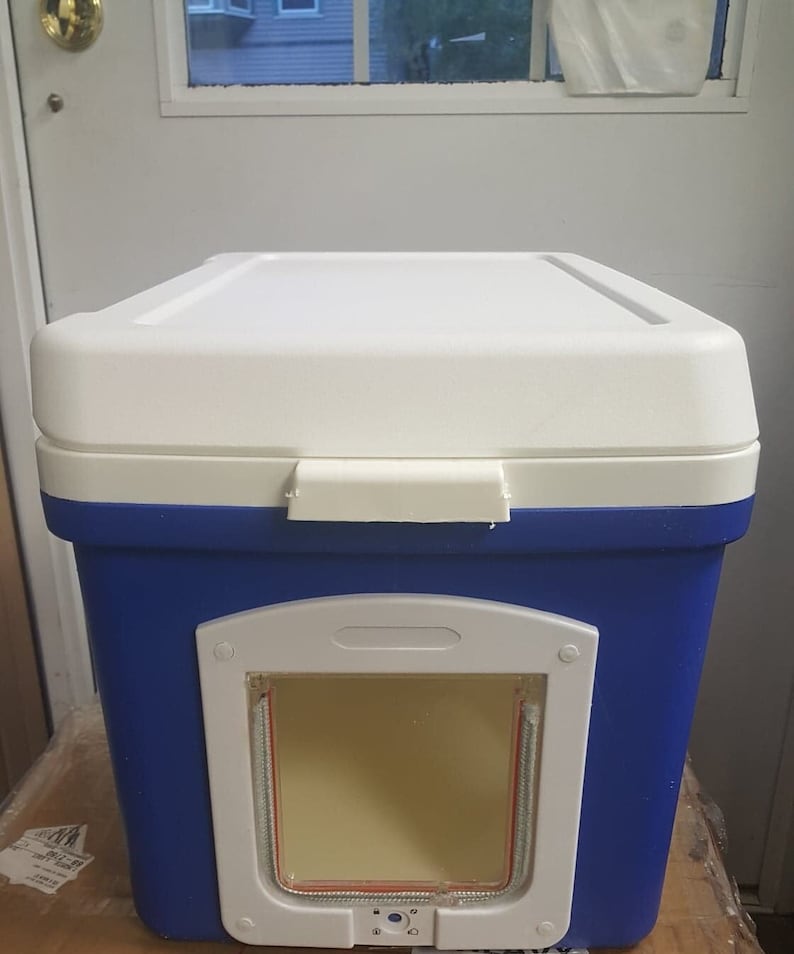 May include: A blue and white cooler with a pet door cut out. The door has a white frame and a clear plastic flap.