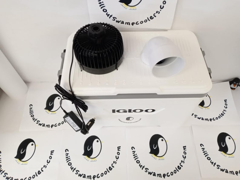 May include: A white Igloo cooler with a black fan, white vent, and power adapter. The cooler has the text "IGLOO" on the front. Several white circular logos with a penguin and the text "chilloutswampcoolers.com" are scattered around the cooler.