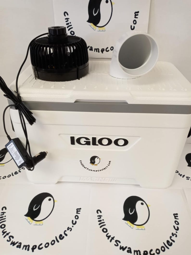 May include: A white Igloo cooler with a black fan, white duct, and power adapter. The cooler has a gray top and the text "IGLOO" in black. The logo "Chillout Swampcoolers.com" is also visible.