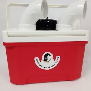 May include: A red and white cooler with a white handle and two white curved pipes on top. A black cap is centered on the lid. A sticker with a penguin and the text "chilloutswamecoolers.com" is on the front.