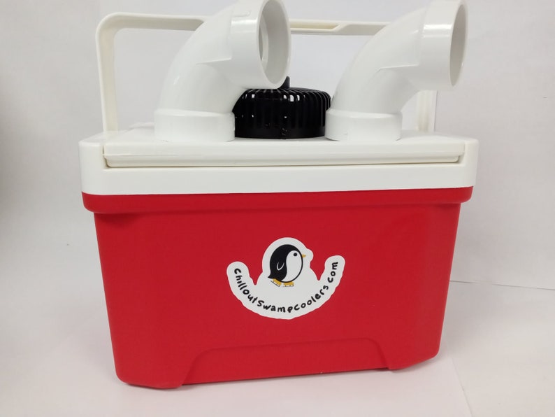 May include: A red and white cooler with a white handle and two white curved pipes on top. A black cap is centered on the lid. A sticker with a penguin and the text "chilloutswamecoolers.com" is on the front.
