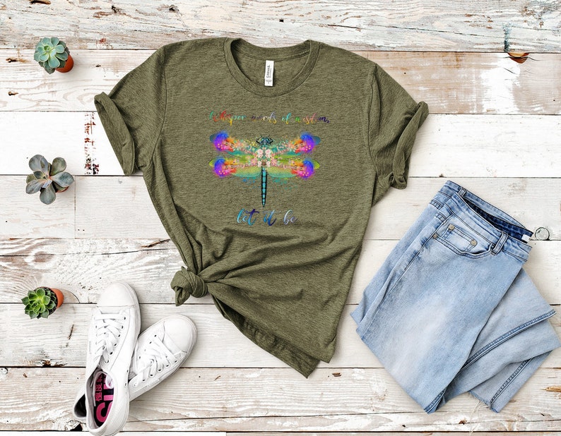 Puede incluir: Una camiseta verde con un dise&ntilde;o de lib&eacute;lula colorido y el texto "Si no puedes dejarlo ir, d&eacute;jalo ser".