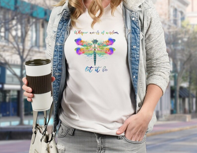 Puede incluir: Camiseta blanca con un gr&aacute;fico de lib&eacute;lula colorido y el texto "Whisper words of wisdom, let it be".