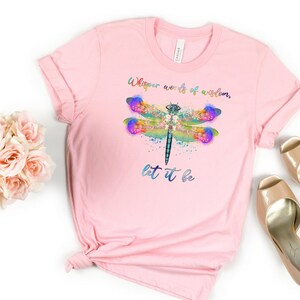 Puede incluir: Camiseta rosa con un dise&ntilde;o de lib&eacute;lula acuarela y el texto "Whisper words of wisdom, let it be".
