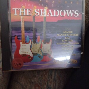 May include: CD case for "The Apaches Play the Hits of The Shadows." The cover shows three electric guitars in red, blue, and cream. The CD includes tracks such as "Apache" and "Man of Mystery."