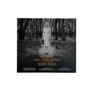 May include: A hardcover book titled "The Art of Miss Peregrine's Home for Peculiar Children" featuring a black and white image of a woman in a dress standing in a forest. The book cover includes text by Tim Burton, Ransom Riggs, and Leah Gallo.