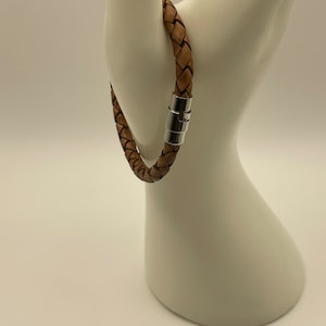 May include: A brown leather braided bracelet with a silver magnetic clasp.
