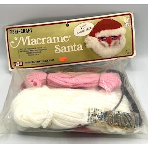 May include: A Fibre-Craft Macrame Santa kit. The kit includes materials for a 15-inch Santa face, with red, pink, and white yarn. The packaging features a Santa face image and the text "Macrame Santa".