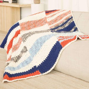May include: A crocheted throw blanket featuring a textured pattern of cream, navy blue, coral, light blue, and grey yarn. The blanket is constructed with a repeating stitch design, showcasing a multi-colored arrangement of stripes and blocks.