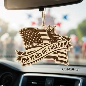 Peut inclure: D&eacute;sodorisant de voiture en bois avec un drapeau am&eacute;ricain, un aigle et le texte "250 YEARS OF FREEDOM" et les ann&eacute;es "1776-2026". Le d&eacute;sodorisant est suspendu &agrave; une ficelle.