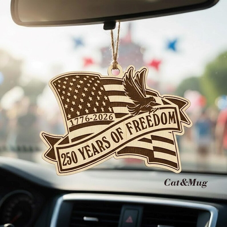 Peut inclure: D&eacute;sodorisant de voiture en bois avec un drapeau am&eacute;ricain, un aigle et le texte "250 YEARS OF FREEDOM" et les ann&eacute;es "1776-2026". Le d&eacute;sodorisant est suspendu &agrave; une ficelle.
