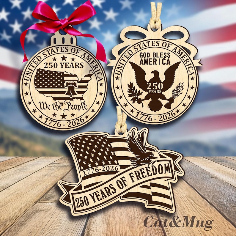 Peut inclure: Trois d&eacute;corations de No&euml;l en bois sur le th&egrave;me patriotique. L'une est ronde avec une carte des &Eacute;tats-Unis et le texte "250 Years" et "We the People". Une autre pr&eacute;sente un aigle et le texte "God Bless America". La troisi&egrave;me est un drapeau avec un aigle et le texte "250 Years of Freedom".