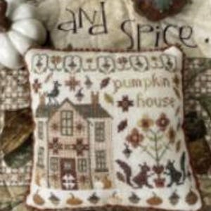 May include: A decorative pillow with a stitched design featuring a house, squirrels, and the words "pumpkin house." The pillow has a cream-colored background with brown and orange accents. The text "and spice" is visible in the background.