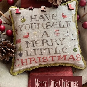 May include: A beige pillow with green fringe, featuring a cross-stitch design that reads "Have Yourself a Merry Little Christmas". The pillow is decorated with red, green, and white accents.
