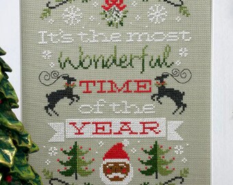 May include: Cross-stitch pattern featuring a festive Christmas scene with the text "It's the most wonderful time of the year". The design includes a Santa Claus, reindeer, and snowflakes.